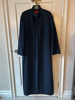 Front view of coat hanging on Holt Renfrew hanger against white door