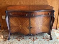 Front view of sideboard showing two drawers and two-door cabinet with book-matched walnut veneer and marquetry inlay