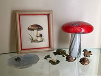 Overview of the lot including framed mushroom painting, Murano glass mushroom sculpture, Royal Copenhagen frog dish, and small figurines.