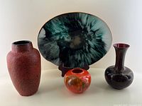 Four mid-century decorative items: two copper enamel vases, one West German fat lava vase, and a painted glass bowl with leather backing.