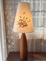 Full front view of lamp showing teak base and floral shade, lit