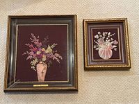 Main photo of two framed floral artworks showing larger porcelain piece on left and smaller shell piece on right.
