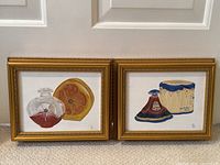 Pair of framed oil paintings side by side showing vintage perfume bottles and boxes, signed RL.