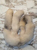 Cream and white fox fur long scarf laid flat on marble floor showing natural darker color gradations.