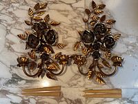 Overhead view of both wall sconces laid flat on marble surface with four taper candles