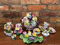 Overview of nine porcelain floral arrangements against brick wall