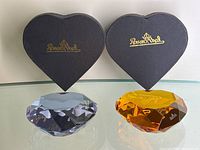 Photo of both crystal heart-shaped paperweights with their original black heart-shaped Rosenthal boxes.