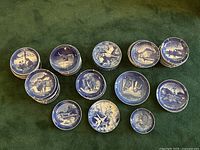 Overhead shot of 23 blue and white plates arranged on green fabric