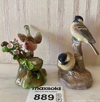 Front view of both bird figurines, robin with nest and fluffy birds on branch side by side.