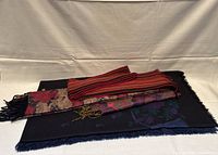 Photo showing three scarves layered on a light background, highlighting varied designs and fringes.