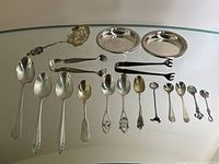 Overview of all items on glass surface: spoons, tongs, coasters, tea strainer