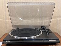 Front view of Technics turntable with dust cover raised, platter and tonearm visible