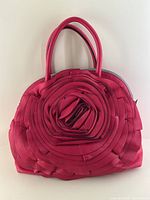 Front view of fuchsia leather handbag displaying spiral rosette design