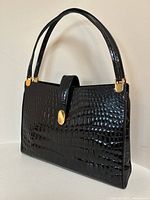 Three-quarter front view showing structured shape, double handles and gold-tone clasp