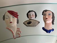 Set of three vintage painted ceramic Art Deco-style wall plaques showing portrait busts of women.