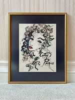 Framed watercolor painting showing full artwork with a stylized female face surrounded by floral elements and 'Coty's Paris' text, in a gold frame with black mat.