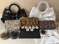 Group shot of all six items including two floral top-handle handbags, three clutches/wallets, and Coach dust bag