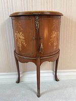 Front view of the demilune side table showing cabinet doors and tapered legs.