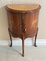 Front view of the demilune side table showing marble top, marquetry doors and cabriole legs