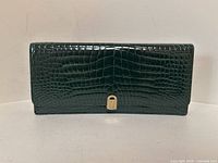 Front view of clutch showing crocodile embossing and gold-tone clasp