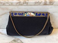 Front view showing black beaded body, gilt frame with blue enamel inlays and painted scene, serpentine chain handle.