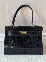 Front view showing crocodile pattern and turn-lock closure