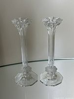Pair of clear vintage Italian crystal candlesticks standing on a reflective surface showing vertical ribbed design and scalloped edge tops
