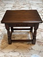 Front view of the oak bench showing turned legs, rectangular top, and carved name 'ELAINE' on front panel.