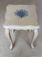 Front angled view showing the floral painted top and curved legs with distressed finish
