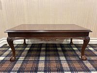 Front view of vintage solid wood coffee table showing carved apron and claw feet.