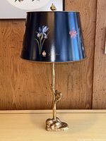 Full view of lamp showing black hand-painted botanical shade and gilded branch base with bird figure