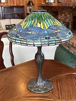 Full frontal view of lamp showing entire stained glass shade and metal base on wood table.