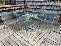 Wide view of four chairs surrounding flower-shaped table base on wood deck