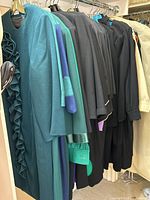 Multiple green and black dresses hung on hangers
