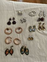 Overview of all 13 earring pairs laid out on light fabric
