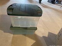 Two stacked clear plastic Rubbermaid totes with dark green lids, shown from the front and side.
