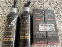 Three bottles of Ahuhu Essential Anti-Age Elixir with Redensyl and two boxed Amino Intensive Repair Hair Serum bottles