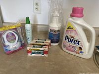Wide view showing all laundry products together on a counter including detergent sheets, stain removers, fabric softener, and soap bars