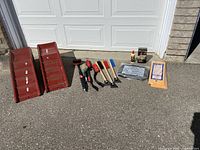 Lot items arranged in a single line on asphalt with garage door background, showing all included brushes, risers, cloths, cleaning products, and knee pad.
