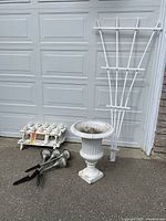 Photo shows overall lot with cast iron flower urn, fence barriers in packages, fan-shaped white garden lattice, and four solar lawn lights.