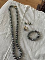 Full set on cloth background: necklace, bracelet, ring, earrings.