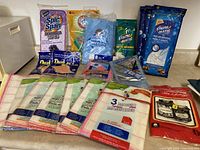 Photo showing assorted cleaning cloth parts and packages including Spic Span wipes, Arm & Hammer cloths, static matic wipes, and dust mitts in original sealed packaging