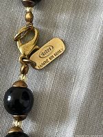 Close-up of lobster claw clasp and tag stamped 'SRM Made in Italy' attached to one necklace.