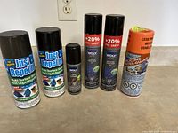 Six bottles and spray cans for fabric and textile water repellency and stain protection on a beige kitchen counter.