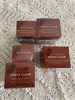 Five boxed Iampure Maple Glow skincare products arranged on fabric.