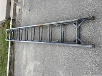 Extension ladder lying on the ground, several metal rungs, used condition