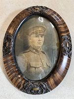 Wide view of the ornate oval wood frame containing the black and white military soldier photo showing frame details and overall condition.