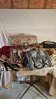 Shows 11 luggage items arranged on a table and chair, including patterned, grey, red, gold, and vintage bags