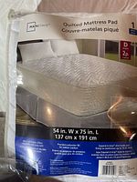 Photo of Mainstays quilted mattress pad package showing product name, size, and features.