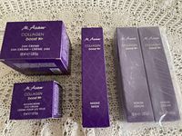 Five M.Asam Collagen Boost skincare products presented on fabric background, consisting of 24H Cream, Eye Cream, Mask, and two Serums in unopened purple packaging.